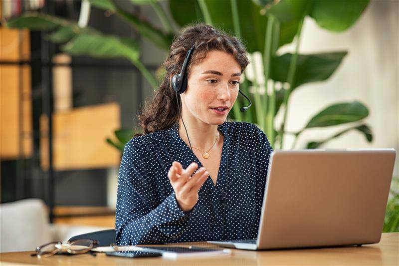 Female sitting at laptop speaking with headset