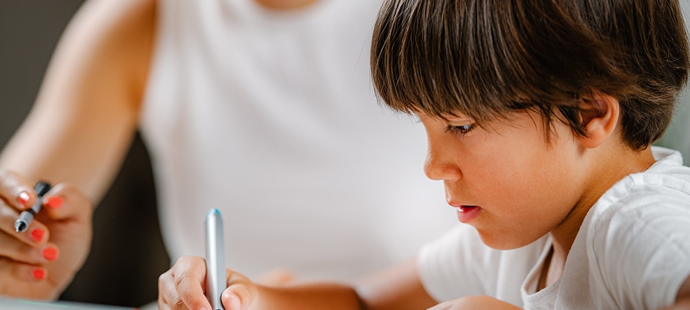 Pupil writing with teacher